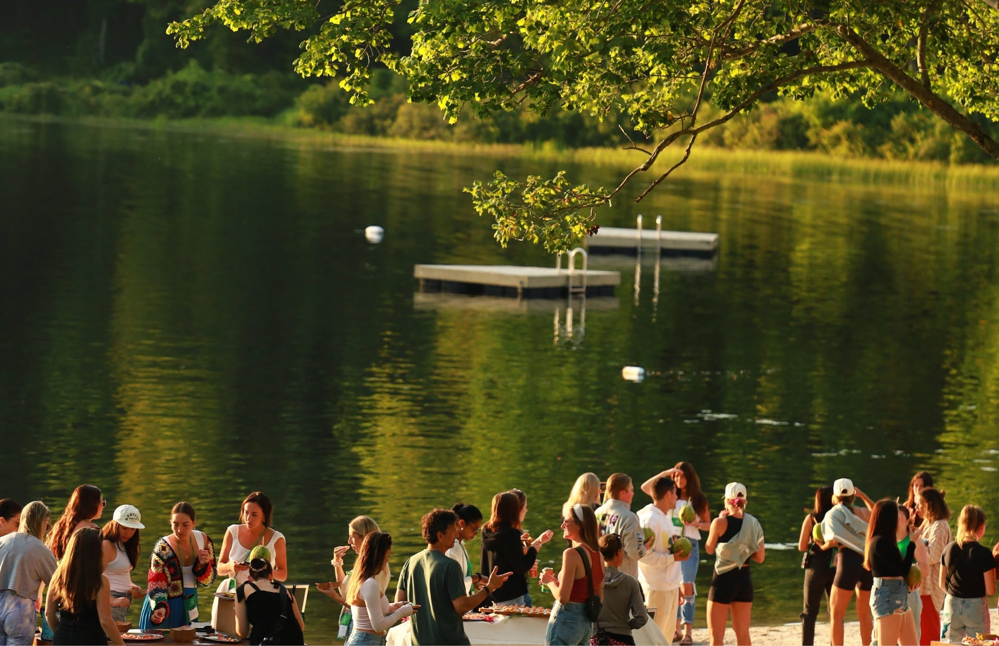 adults gathered by a lakeside dock at summer camp